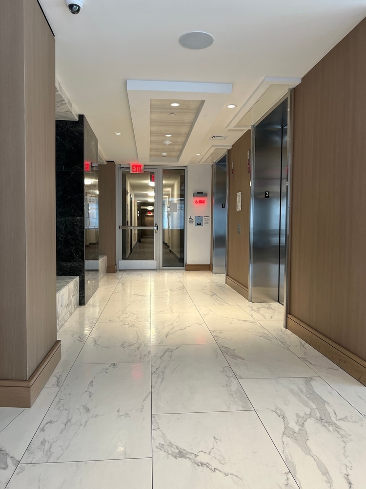 Lobby moderne : sol marbre, ascenseurs et design bois Hall moderne avec sol en marbre blanc, murs en bois, ascenseurs et panneau EXIT rouge.