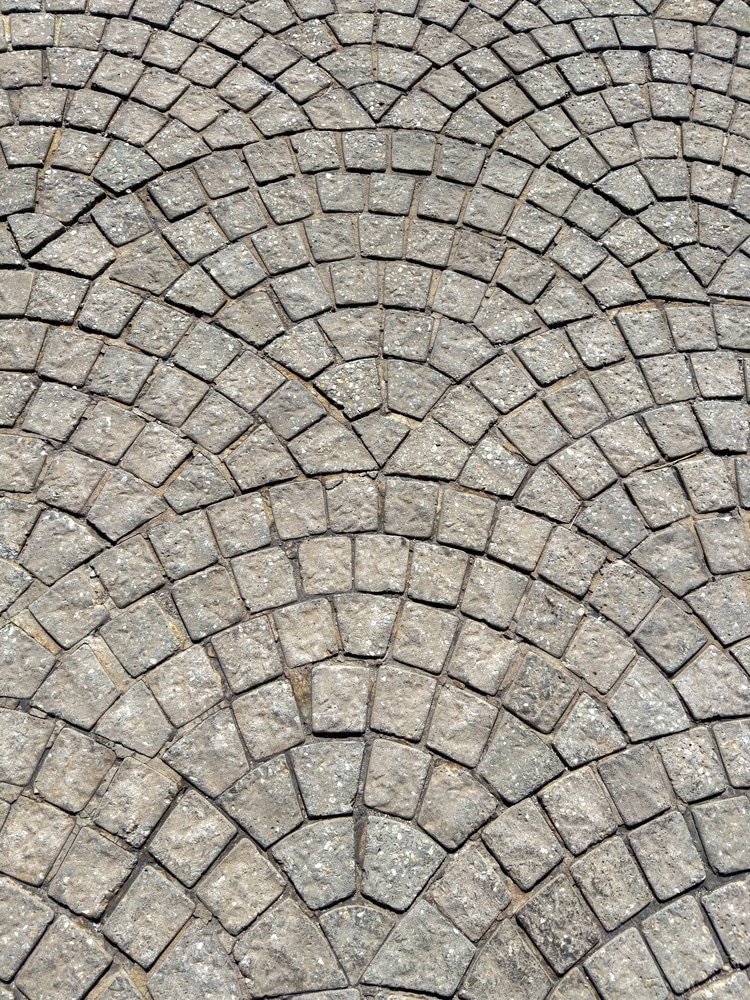 Pavés en Éventail : Sol en Pierre Naturelle pour Extérieur Pavés en pierre grise disposés en motif d'éventail sur un sol extérieur texturé.