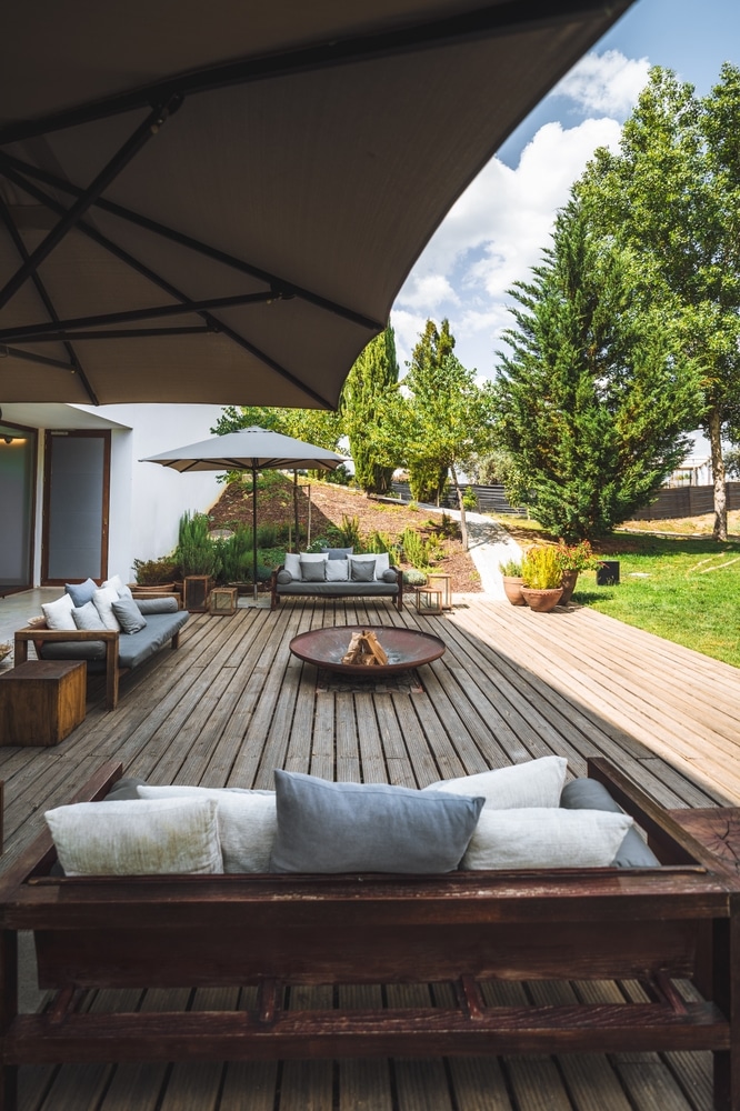 Aménagement de Terrasse en Bois avec Brasero et Salon Salon de jardin moderne sur terrasse en bois avec brasero, fauteuils confortables et parasols sous le soleil.